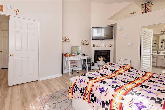 bedroom featuring light wood-type flooring, visible vents, a fireplace, and baseboards