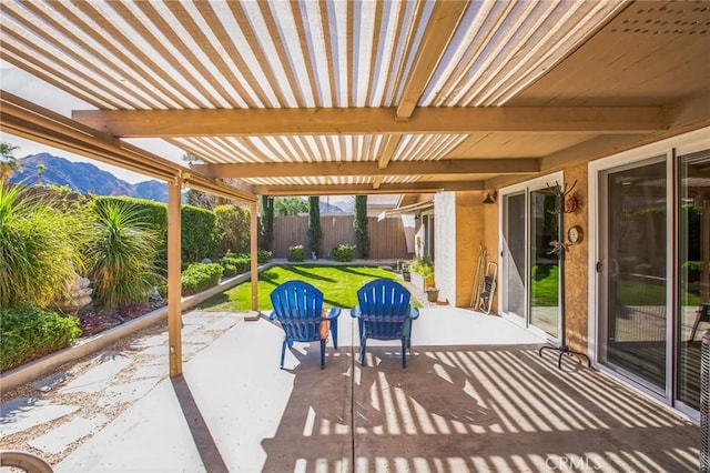 view of patio with a mountain view and fence