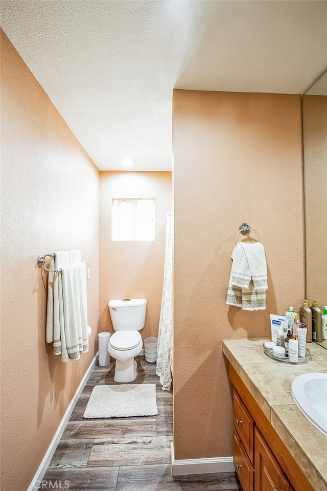 full bathroom featuring baseboards, vanity, toilet, and wood finished floors