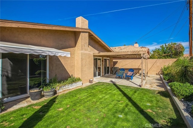 back of property featuring a lawn, a patio, a chimney, fence, and stucco siding