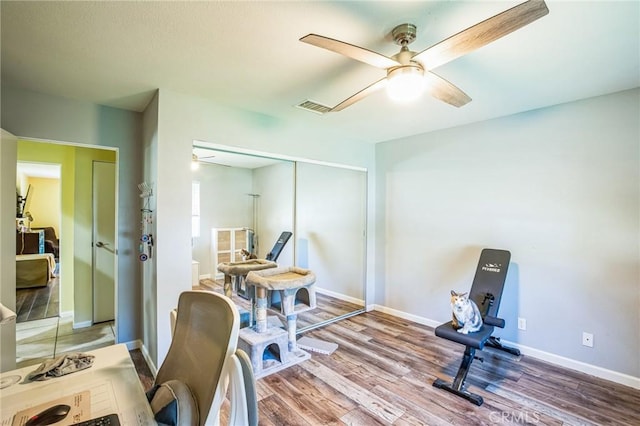 workout area featuring baseboards, wood finished floors, visible vents, and a ceiling fan