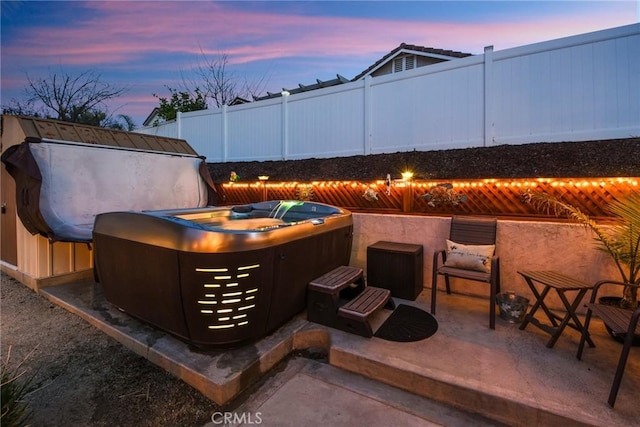 view of patio with a hot tub and fence