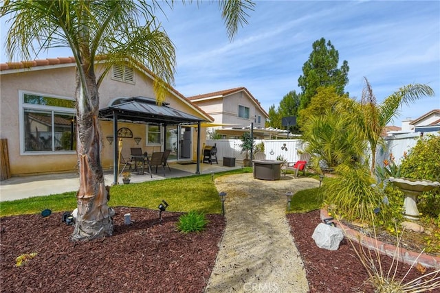 rear view of property with an outdoor fire pit, a gazebo, a patio area, and stucco siding