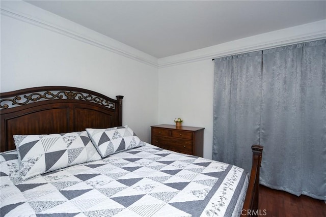 bedroom featuring ornamental molding and dark wood-style flooring