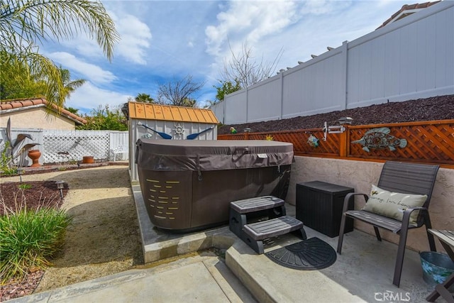 view of patio with an outbuilding, a fenced backyard, and a hot tub