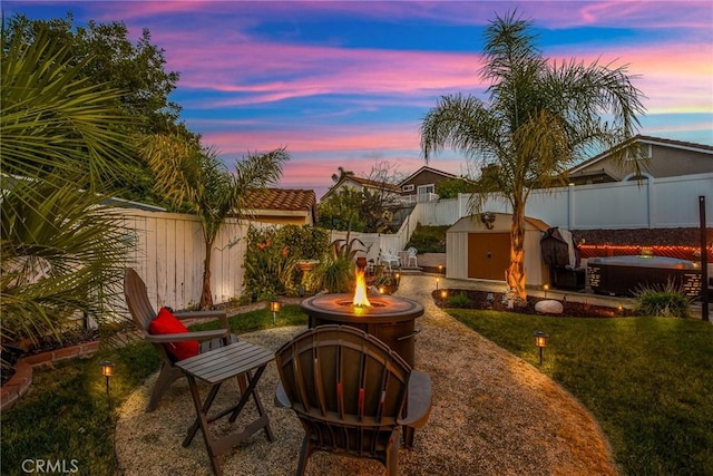 view of patio with an outdoor fire pit, a fenced backyard, an outbuilding, and a storage unit