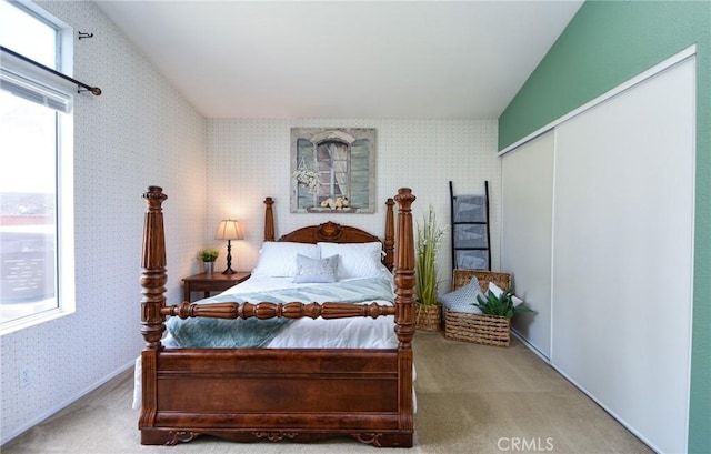 carpeted bedroom with lofted ceiling, a closet, and wallpapered walls