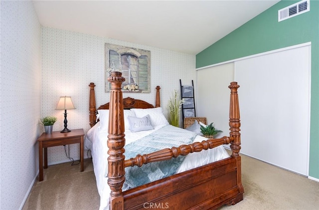 bedroom featuring wallpapered walls, visible vents, carpet, vaulted ceiling, and a closet