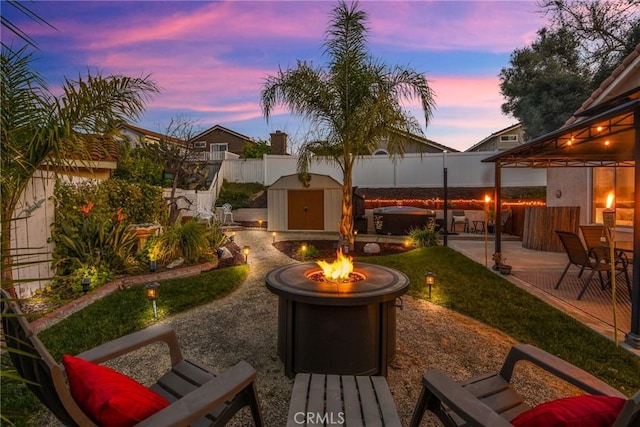 view of yard featuring an outdoor fire pit, a patio, a fenced backyard, a storage unit, and an outdoor structure