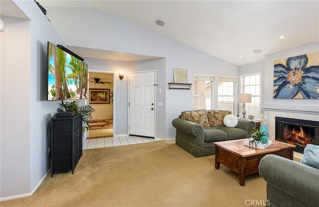 living room featuring carpet, lofted ceiling, a tiled fireplace, baseboards, and tile patterned floors