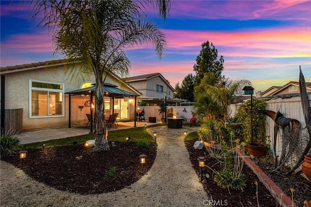 back of property at dusk with a patio area, a fenced backyard, and stucco siding