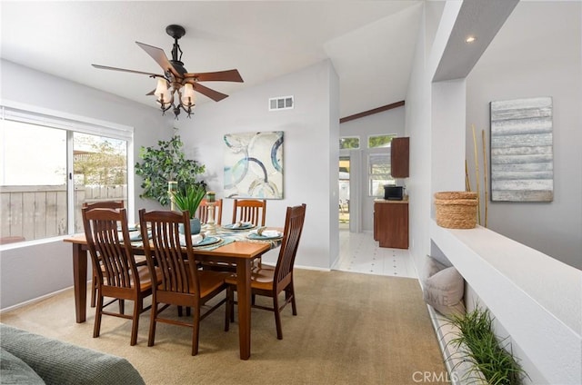 carpeted dining space featuring lofted ceiling, ceiling fan, and visible vents