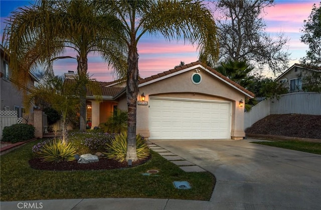 view of front facade with a garage, concrete driveway, a tile roof, fence, and stucco siding