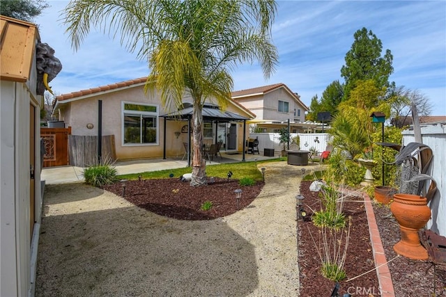 back of property with a gazebo, a patio area, a fenced backyard, and stucco siding