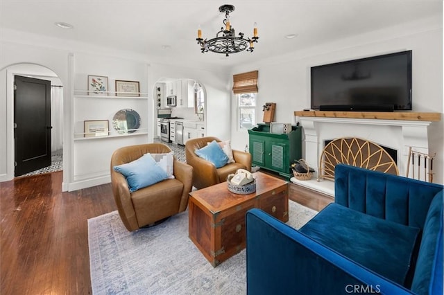 16070 Baker Canyon Rd, Canyon Country, CA 91390 - living area with a fireplace with raised hearth, wood finished floors, arched walkways, baseboards, and a chandelier