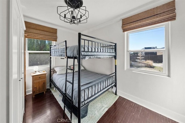 bedroom with dark wood-style floors, ornamental molding, a notable chandelier, and baseboards