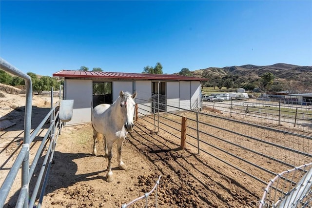 view of horse barn with a rural view and a mountain view