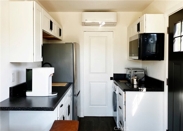 16070 Baker Canyon Rd, Canyon Country, CA 91390 - kitchen featuring dark countertops, white cabinets, a wall mounted air conditioner, and black microwave