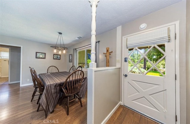 dining room featuring a textured ceiling, wood finished floors, visible vents, and baseboards