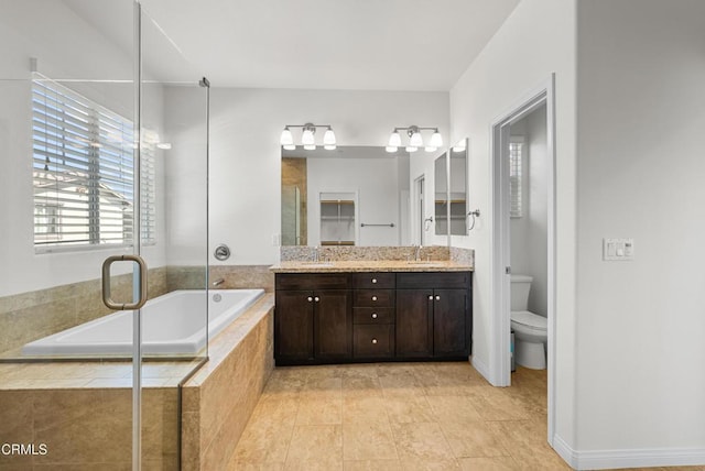 full bath featuring a garden tub, a sink, toilet, and double vanity