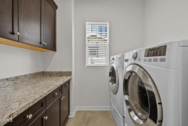 laundry area with cabinet space, independent washer and dryer, baseboards, and light tile patterned floors