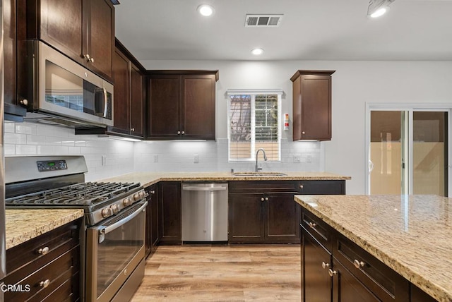 kitchen with light stone counters, appliances with stainless steel finishes, a sink, and visible vents