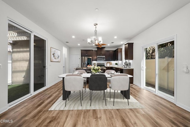 dining room with a chandelier, recessed lighting, baseboards, and light wood-style floors