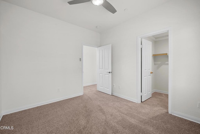 unfurnished bedroom featuring carpet floors, a spacious closet, and baseboards