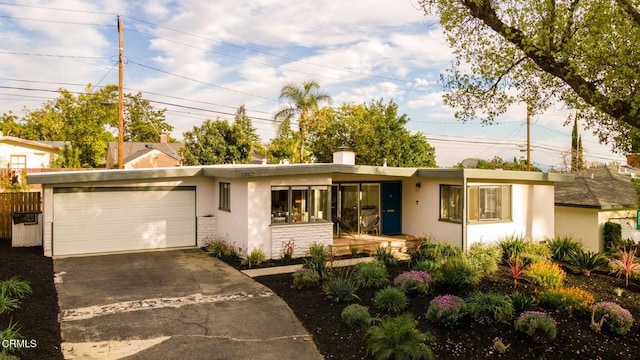 ranch-style home featuring a garage, concrete driveway, and stucco siding