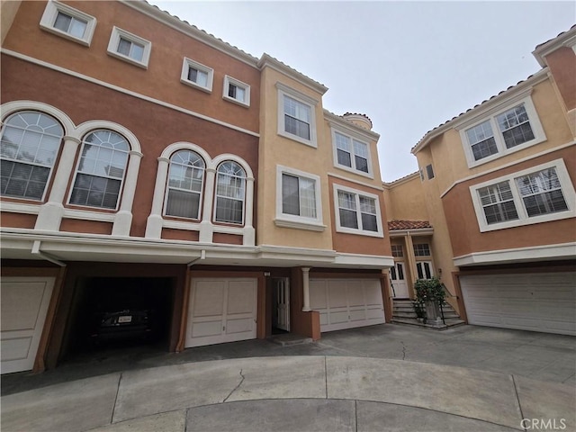 view of property featuring a garage, driveway, and stucco siding