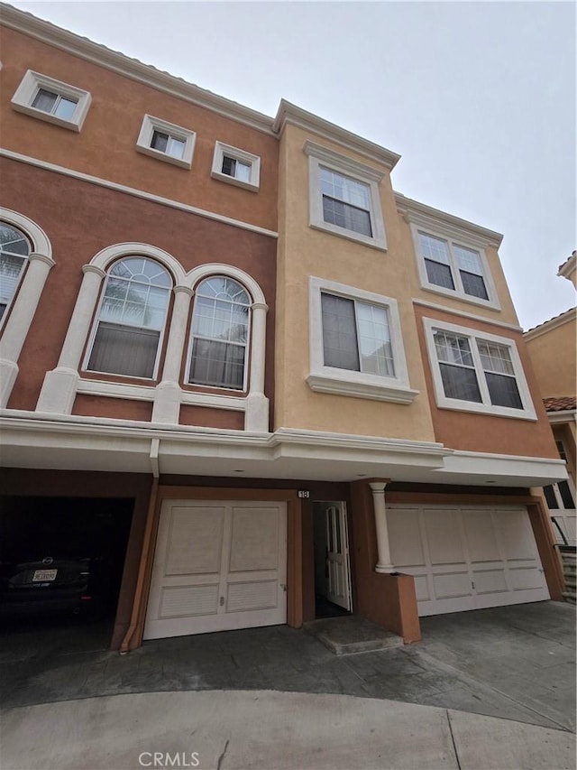 view of property featuring an attached garage and stucco siding