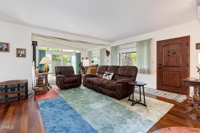 living area with a healthy amount of sunlight, wood finished floors, and lofted ceiling