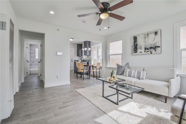 living room with a ceiling fan, recessed lighting, baseboards, and light wood finished floors