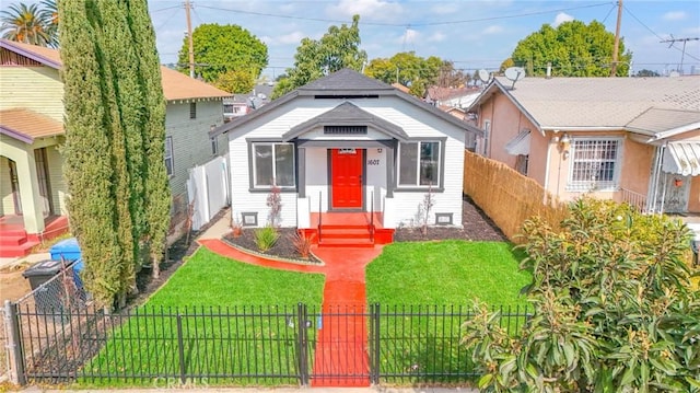 bungalow-style home featuring a front lawn and a fenced front yard