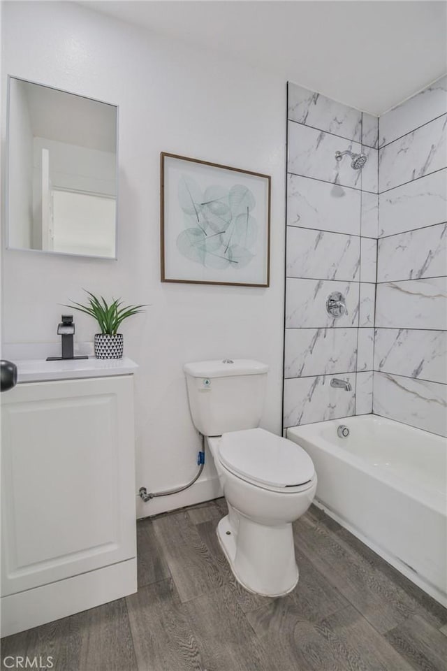 full bathroom with baseboards, toilet, wood finished floors, vanity, and shower / bathing tub combination