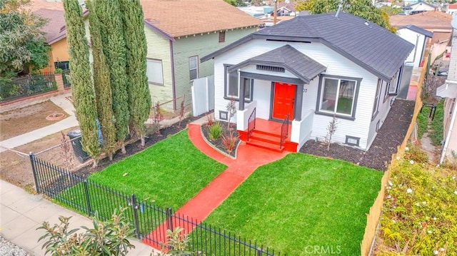 bungalow featuring a shingled roof, a fenced front yard, and a front yard