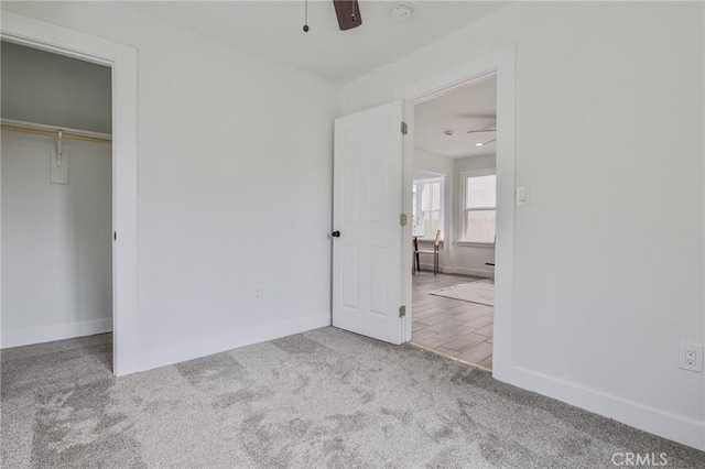 unfurnished bedroom featuring a closet, carpet flooring, a ceiling fan, and baseboards