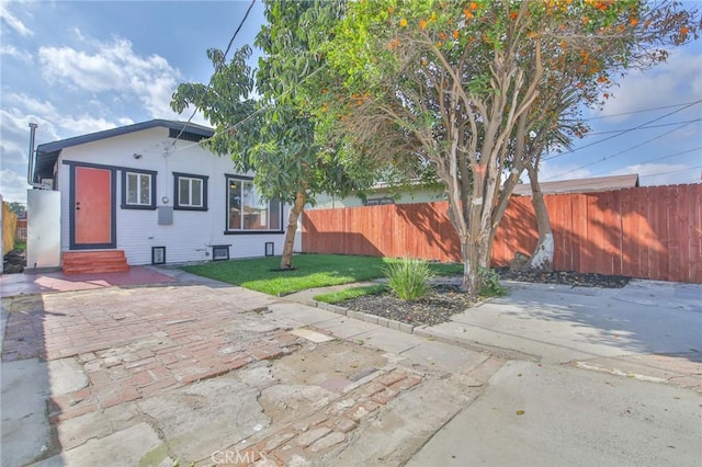 view of front of home with entry steps, fence, and a front yard