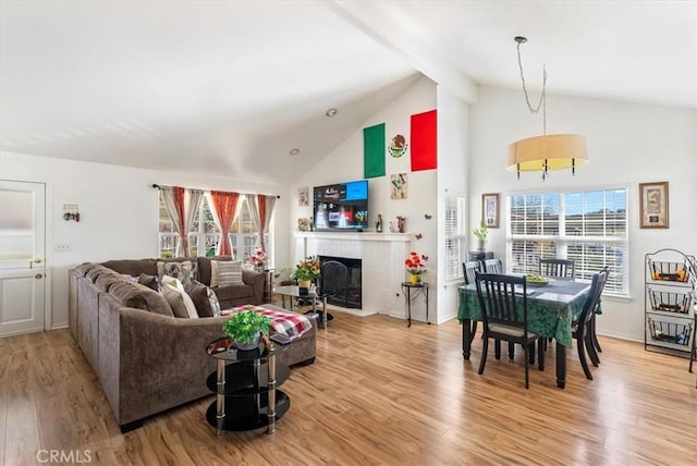 living room featuring light wood finished floors, a brick fireplace, high vaulted ceiling, beamed ceiling, and baseboards