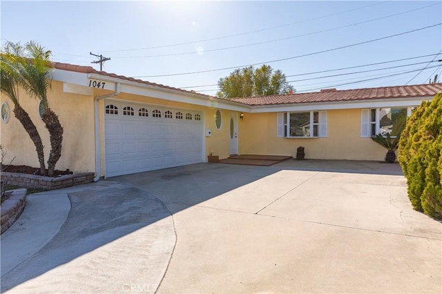 ranch-style house with a garage, a tile roof, concrete driveway, and stucco siding