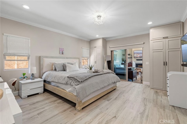 bedroom featuring light wood-style floors, a warm lit fireplace, crown molding, and baseboards