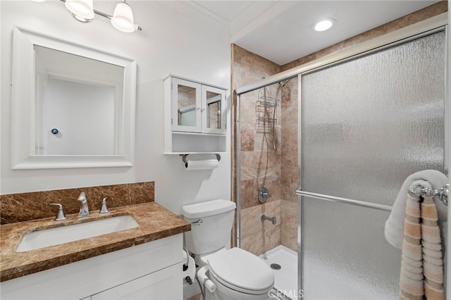 bathroom featuring ornamental molding, a stall shower, vanity, and toilet