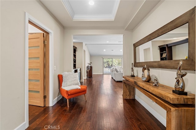 hall with ornamental molding, a tray ceiling, baseboards, and hardwood / wood-style flooring