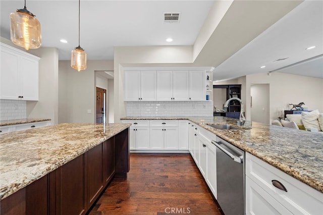 kitchen with light stone counters, dark wood finished floors, visible vents, stainless steel dishwasher, and a sink