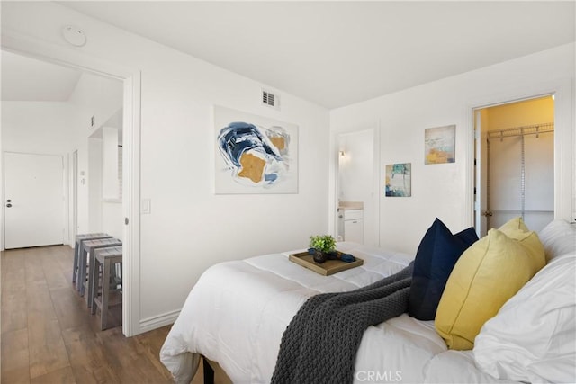 bedroom featuring visible vents, wood finished floors, and ensuite bathroom