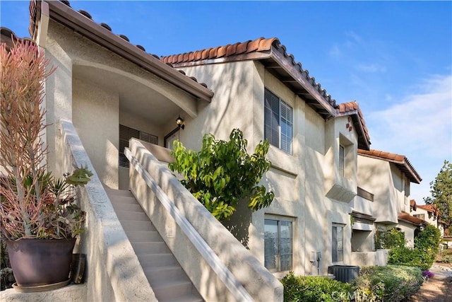 view of side of home with a tile roof and stucco siding