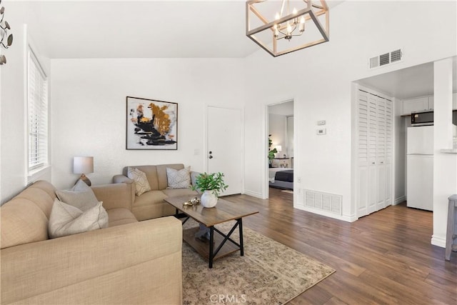 living area featuring high vaulted ceiling, wood finished floors, visible vents, and baseboards