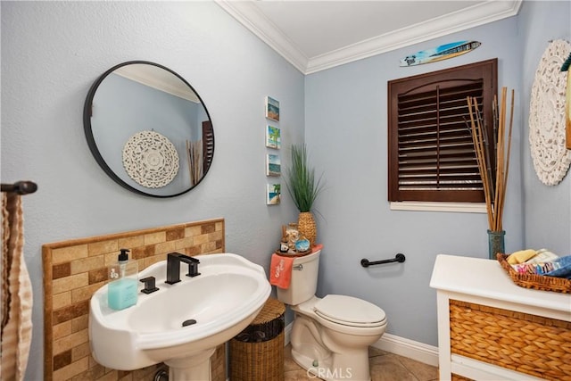 bathroom with toilet, ornamental molding, a sink, baseboards, and tile patterned floors