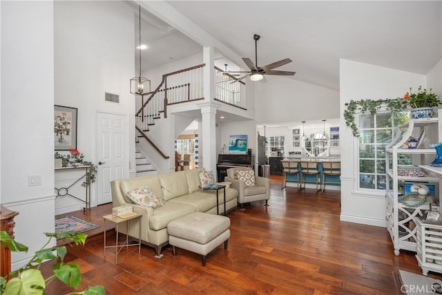 living area with stairs, visible vents, wood finished floors, high vaulted ceiling, and ceiling fan with notable chandelier