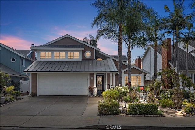 view of front of home with an attached garage, a standing seam roof, metal roof, and concrete driveway